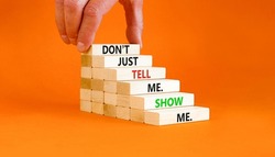 Tell or show symbol. Concept words Do not just tell me, show me on wooden blocks. Beautiful orange table orange background. Businessman hand. Business tell or show concept. Copy space.