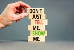 Tell or show symbol. Concept words Do not just tell me, show me on wooden blocks. Beautiful grey table grey background. Businessman hand. Business tell or show concept. Copy space.