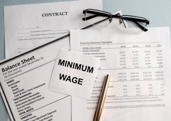 a paper with MINIMUM WAGE text on backgrounwith documents and glasses
