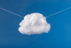Cotton cloud hanging in blue sky on strings. Surrealism style. High quality photo