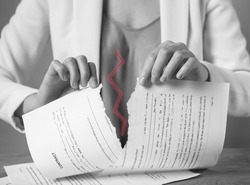 Torn document in hands. Breaking contract. Sanctions, agreement conditions and rules breaching, force majeure. Woman ripping paper agreement. Black and white. High quality photo