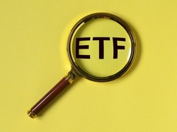 ETF acronym through magnifying glass on yellow background. High quality photo