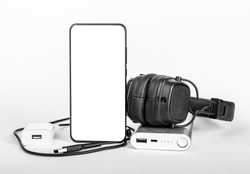 Mobile phone screen mockup, smartphone display mock up with stuff for travel. Headphones, portable charger, cords, wires. High quality photo