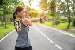 Fitness woman doing stretch exercise stretching her arms - tricep and shoulders stretch wearing a smartwatch activity tracker. Women stretching for warming up before running or working out.