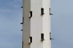 Close up of an old and white lighthouse. front view of a tall tower with a lot of windows. working lighthouse on a beach in tarragona, spain
