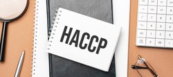 haccp on notepad and various business papers on brown background. Brown glasses and magnifier with notepad.