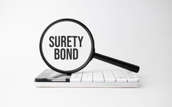 Finance and business concept. On a white background lies a calculator and a magnifying glass with the inscription - Surety Bond