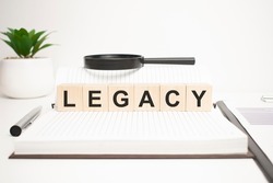 legacy word concept. wooden cubes, notepad, pen and business charts.