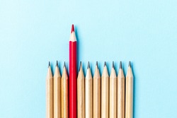 One red pencil standing out from the series of colorful pencils. On blue background. Sign symbol idea concept of leadership, divergent, diversity. Standoff of the individual to society