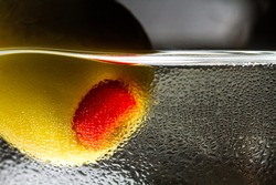 Close-up of olive with pepper in a martini glass with drops