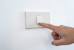 Man's fingers were turning off or turning the light switches on the white wall. Every time when not used for energy saving, electric energy saving concept.