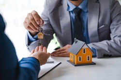 Real estate company to buy houses and land are delivering keys and houses to customers after agreeing to make a home purchase agreement and make a loan agreement. Discussion with a real estate agent 