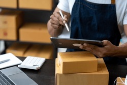 Freelance businessman checking and verifying shipping information Package boxes to prepare for delivery to customers who order online on laptop computers and tablets. ecommerce startup business ideas