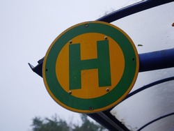 A yellow and green bus stop sign is attached to a busstop.