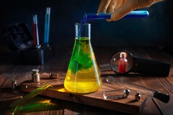 scientist pours blue liquid into yellow in a chemical flask. color change. science, experiments