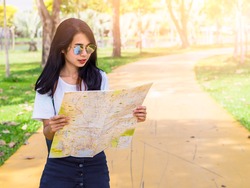 Hipster girl with backpack using and looking at map.Person visiting the sights on holiday. sun flare