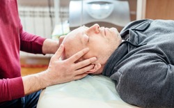 Male patient receiving cranial sacral therapy, lying on the massage table in CST osteopathic clinic, osteopathy and manual therapy