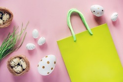 Easter shopping background with green shopping bag with Easter eggs and bird's nest on pink background