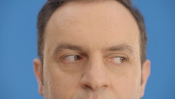 Close-up eye in front of a blue background, young man moving his eyes left and right. Looking left and right, up and down with his eyes.