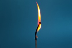 Burning match on a blue background.  source of fire.  Beautiful fiery silhouette from a match