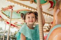 a little girl in a blue dress rides on an attraction in an amusement park
