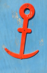      wooden red anchor on a blue wooden surface with peeling paint     