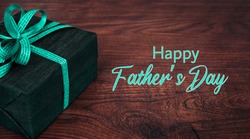 wooden surface with a gift and the text: Happy fathers day. Greeting card, banner or poster for father's day. Photo with commercial letters and the text for father's day. Copy space.