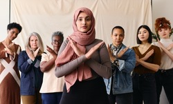 Middle Eastern woman wearing hajib gesturing Break The Bias in support of International Women's Day with female friends