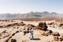 People in love kiss in the crater of the Teide volcano. Desert landscape in Tenerife. Teide National Park. Desert crater of the Teide volcano. Tenerife, Canary Islands