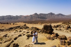 People in love kiss in the crater of the Teide volcano. Desert landscape in Tenerife. Teide National Park. Desert crater of the Teide volcano. Tenerife, Canary Islands.