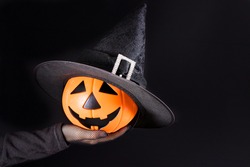A hand holds a pumpkin lantern jack on a black. Accessories for Halloween. Copy space for text
