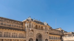 The facade of the ancient palace in Amber Fort. Domes with spires, lattice windows, arches, galleries are visible. Blue sky. India. Jaipur