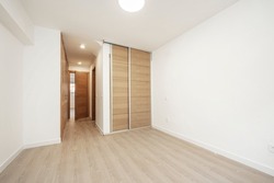 Bedroom with fitted wardrobes with sliding doors and normal doors in light oak wood and floors of the same material