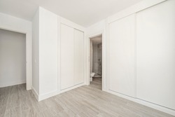 Room with white fitted wardrobes with wooden sliding doors and stoneware floors