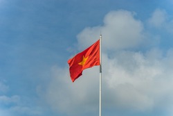 Waving Flag of Vietnam with beautiful sky and clouds. Red flag with yellow star, blue sky with clouds in background. National flag of Vietnam. Popular country for tourism.