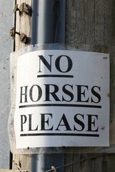A sign saying no horses please on a lamp post