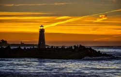 The silhouette of the lighthouse at sunset. Lighthouse at sunset sea. Sea sunset lighthouse. Sunset lighthouse