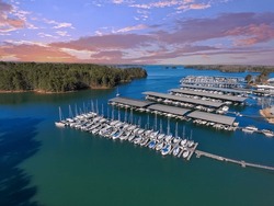 Boats and yachts docked and sailing in the marina on Lake Lanier with lush green trees and and powerful clouds at sunset in Cummings Georgia USA