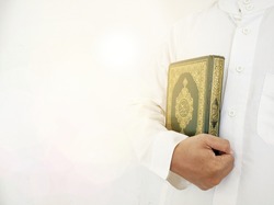 Man Holding and reading quran. Islamic Background. Arabic on the text translated with Quran