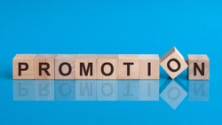 Word promotion is made of wooden building blocks lying on the table and on a light blue background. Promotion - word from wooden blocks with letters.