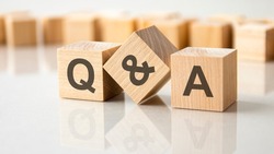 Three wooden cubes with the letters Q and A on the bright surface of a gray table. the inscription on the cubes is reflected from the surface of the table. Q and A - short for question and answer
