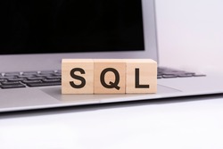 SQL - wooden cubes with letters on a silver laptop keyboard. SQL - short for Structured Query Language. business conceptual word collected of of wooden elements with the letters.