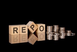 REPO. wooden cubes. black background. stacks with coins. inscription on the cubes is reflected from the surface of the table. business concept. REPO - short for Repurchase Agreement