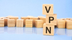 vpn. wooden cubes. blocks lie on a black background. stacks with coins. inscription on the cubes is reflected from the surface of the table. selective focus. vpn - short for virtual private network.