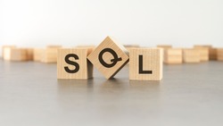 wooden cube with the letter from the SQL word. wooden cubes standing on gray background. SQL - short for Structured Query Language.