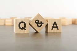 three wooden blocks with letters QA with focus to the single cube in the foreground in a conceptual image, grey background, question and answer concept