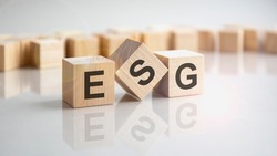 ESG - Environmental Social Governance - an abbreviation of wooden blocks with letters on a gray background. reflection of the caption on the mirrored surface of the table.