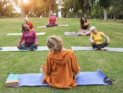 Multiracial people doing yoga sitting with social distance for coronavirus outbreak at park - Healthy lifestyle, sport and multi generational people concept
