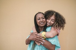 Happy african mother and adult daughter hugging together outdoor - Family love
