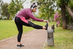 Young curvy woman doing stretching exercise after sport workout routine at city park